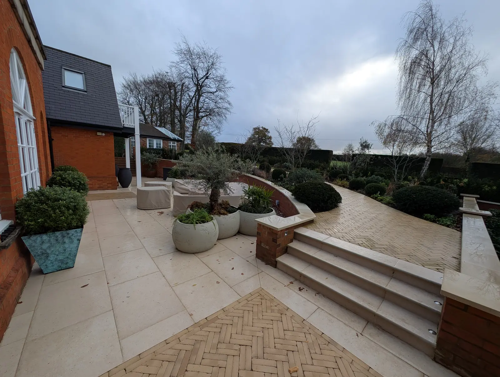 Limestone terrace with herringbone clay paver inlays, new steps and refurbished brick retaining walls