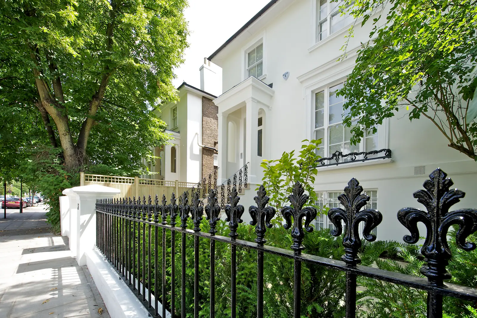 Completed exterior renovation in St John's Wood: white render, restored ornamental railings and new planting behind the boundary wall